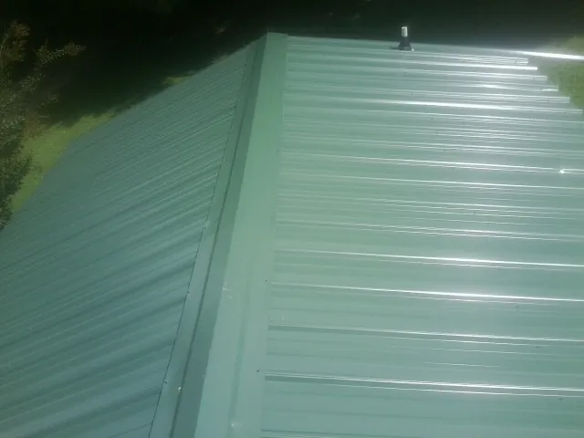 New green metal panels meeting at the ridge of a roof — Flat Roof Repair work by our crew in Soquel