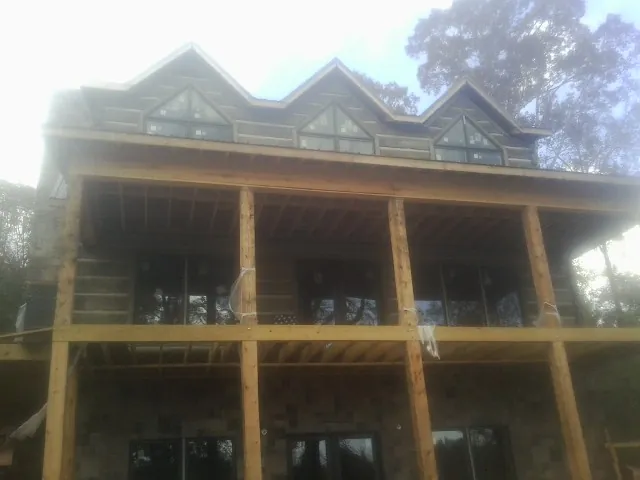 Dormers and porch framing on a large log home under construction — Roof Coating work by our crew in Soquel